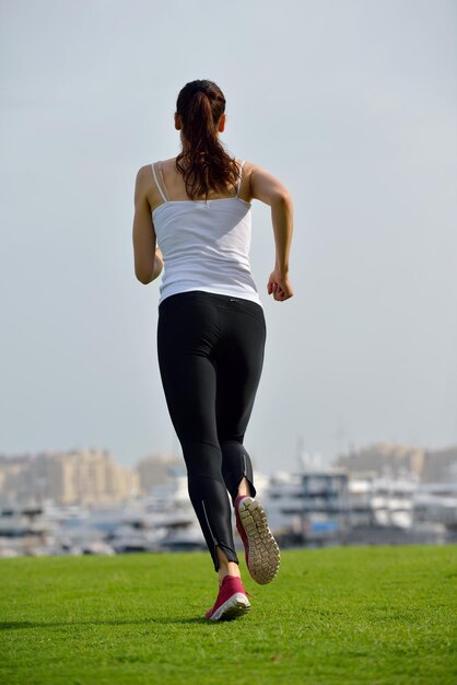 Corriendo en el parque de la ciudad. Mujer corredor fuera de jogging por la mañana con la escena urbana de Dubai en segundo plano.