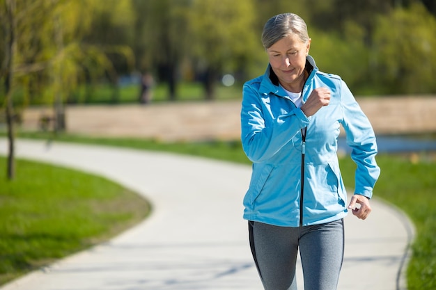 Corriendo en el parque Una mujer madura y guapa corriendo en el Parque y pareciendo contenida
