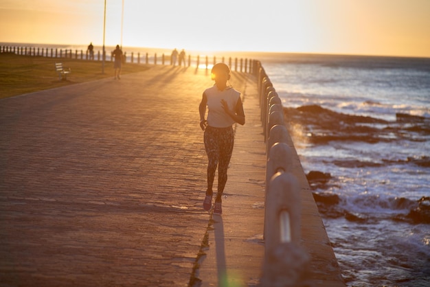 Corriendo por su ruta favorita al atardecer Una joven corriendo por el paseo marítimo al atardecer