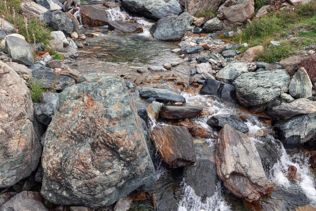 Corriente alpina transparente lavando rocas de granito con minerales de metales Cogne Valle de Aosta Italia