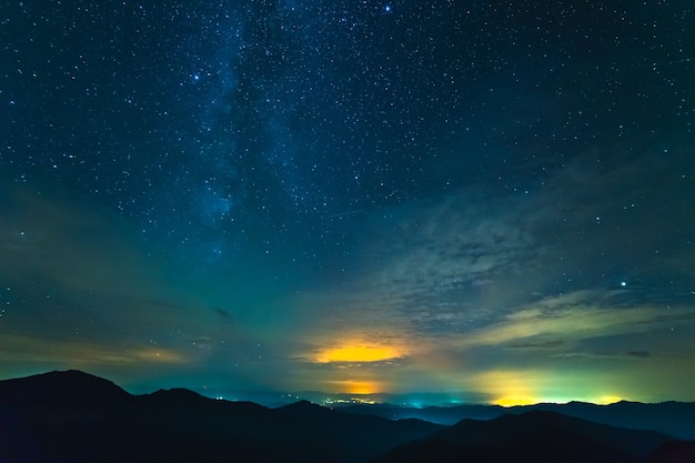 La corriente de nubes sobre montañas con estrellas. tarde noche