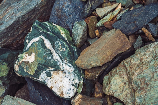 Corriente de rocas multicolores. Roca suelta de cerca. Piedras dispersas al azar en la naturaleza. Increíbles rocas de las tierras altas detalladas con musgos y líquenes. Textura natural del terreno de montaña.