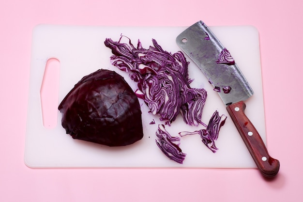 Corta el repollo rojo en una tabla de cortar. Colorante alimentario natural. El proceso de cortar la ensalada. Cuchillo.