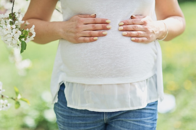 Cortada a imagem da bela jovem grávida tocando sua barriga nua