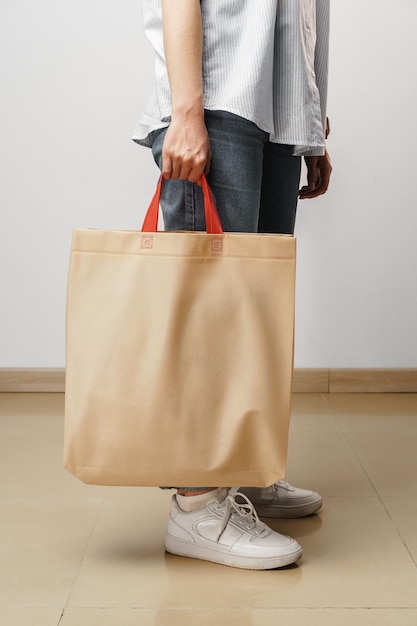 Cortada a imagem da mulher segurando a sacola de compras bege no estúdio
