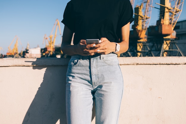 Cortada a imagem de uma garota esbelta em jeans com um telefone