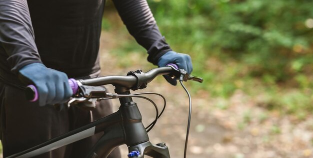 Cortada a imagem do guidão da bicicleta esportiva no fundo da floresta