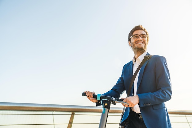 Cortada a imagem do jovem empresário de terno andando de scooter elétrica