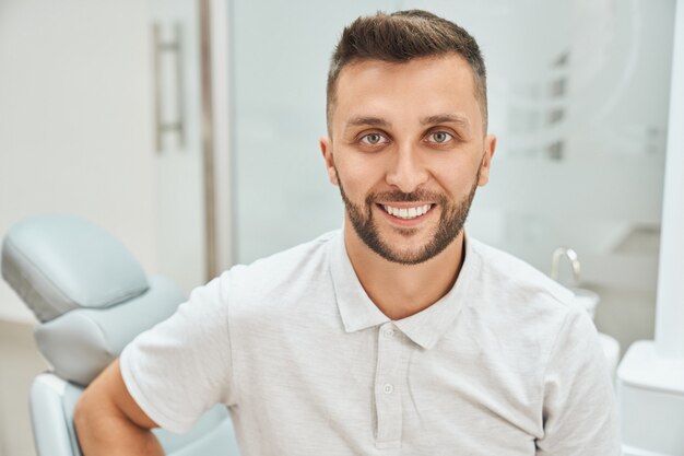 Foto cortada a vista do homem alegre barbudo visitando o consultório odontológico