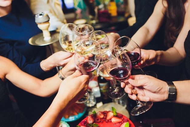 Cortada perto foto de copos com champanhe. os jovens estão brindando para comemorar o evento. a mesa está cheia de comidas e bebidas saborosas.