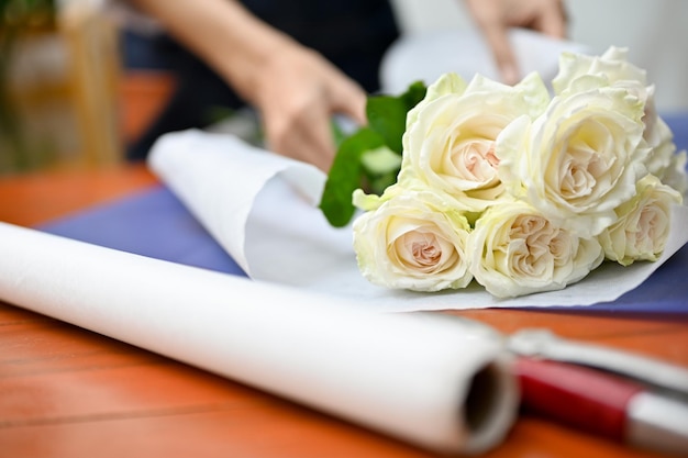 Cortada Uma florista feminina organizando o buquê de rosas brancas para seu cliente