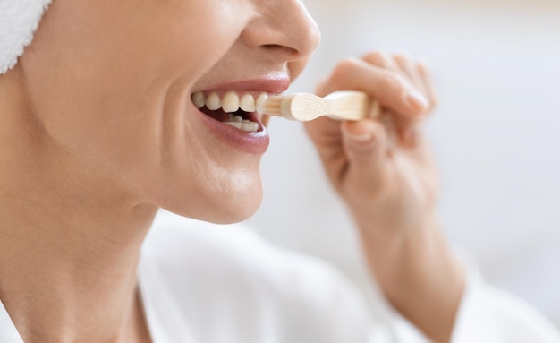 Cortado de mulher escovando os dentes após o banho