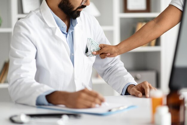 Foto cortado de paciente colocando dinheiro no bolso do casaco médico