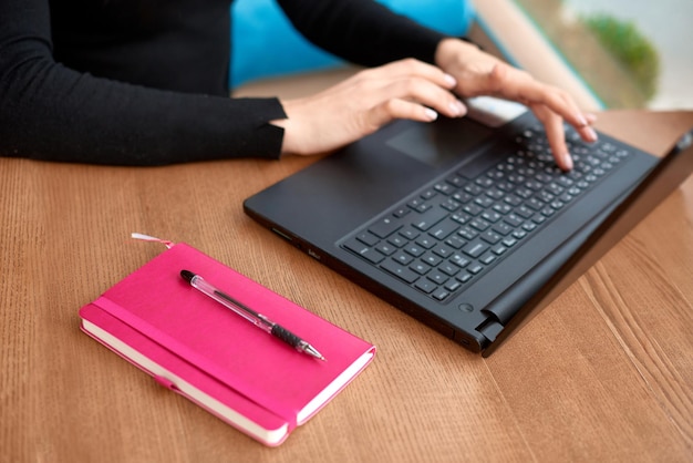 Cortado de trabalhador de escritório sentado à mesa no café Mãos femininas digitam texto longo no teclado no laptop