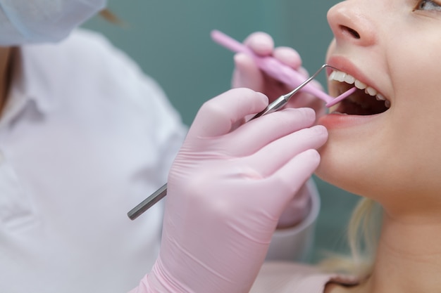 Cortado em close de uma mulher tendo seus dentes examinados e curados por dentista profissional