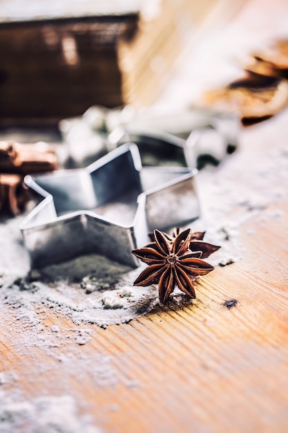 Cortador de biscoitos de anis estrelado, canela e farinha na tábua de cozimento Conceito de férias e bolos de Natal