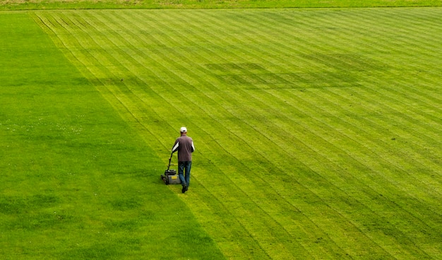 Cortador de grama corta grama no campo de futebol enquanto trabalha