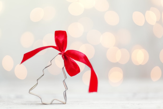 Cortador de galletas de árbol de Navidad con lazo rojo sobre fondo blanco con espacio de copia. Concepto de navidad.