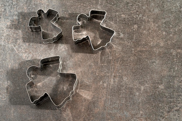 Cortador de galletas de metal en forma de ángel sobre un fondo oscuro