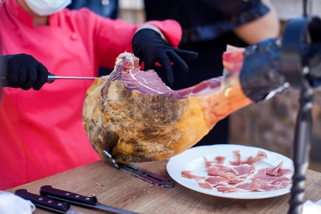 Cortador profissional esculpindo fatias de um presunto inteiro com osso serrano Comida espanhola