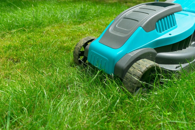 Cortadora de césped cortando hierba verde Trabajo de verano en el jardín