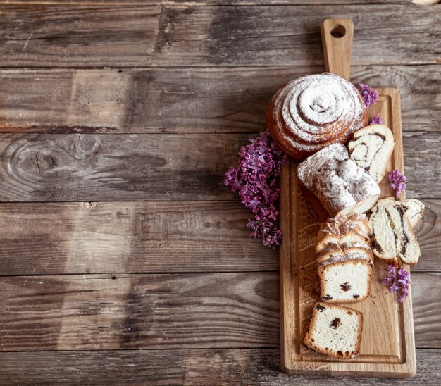 Se cortan diferentes pasteles frescos en un palo de madera, decorado con flores de color lila vista superior.
