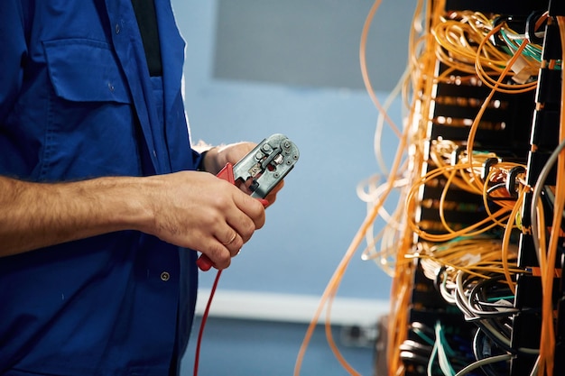 Cortando el cable El joven está trabajando con equipos de Internet en la sala de servidores