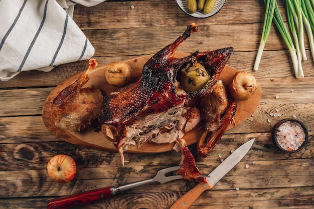 Cortando o pato assado e as maçãs para um jantar festivo em um fundo rústico de madeira Foto seletiva