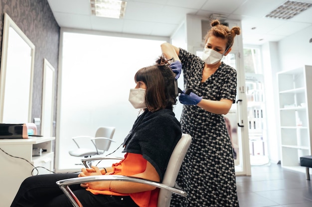 Cortando las puntas a una clienta morena con mascarilla