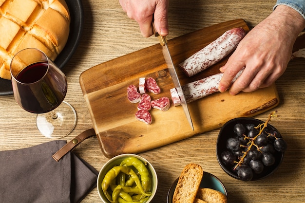 Cortando uma linguiça curada em uma mesa de madeira