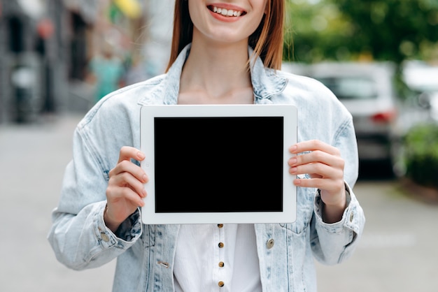 Cortar a imagem de uma menina segurando a tela preta do modelo do ipad nas mãos dela.