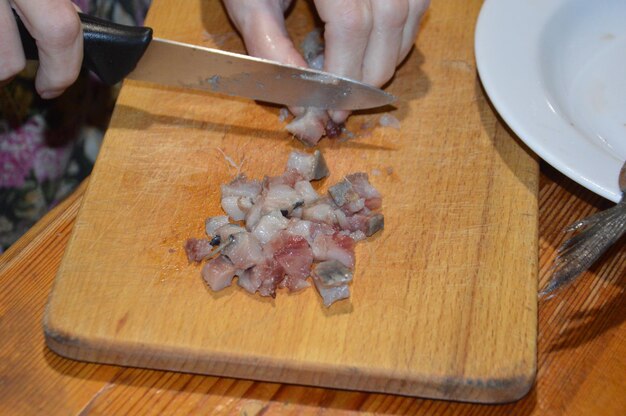 Cortar arenque com uma faca na tábua da cozinha