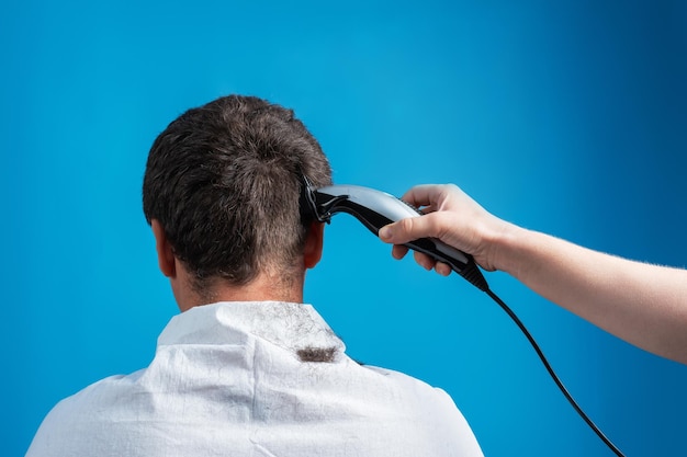 Cortar el cabello de los hombres con una máquina eléctrica en condiciones caseras simples Imagen aislada