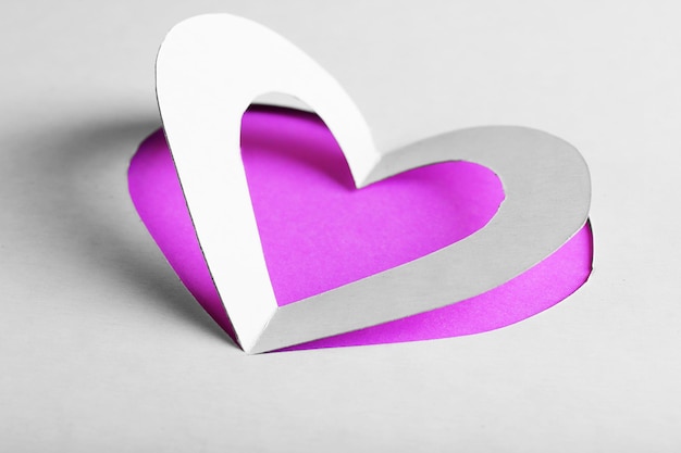 Cortar el corazón de papel blanco sobre fondo morado