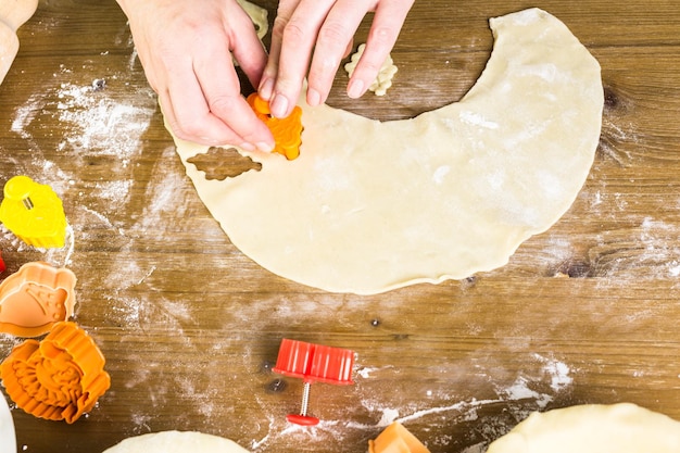 Cortar folhas de outono com estampador de biscoito para decorar a torta de abóbora.