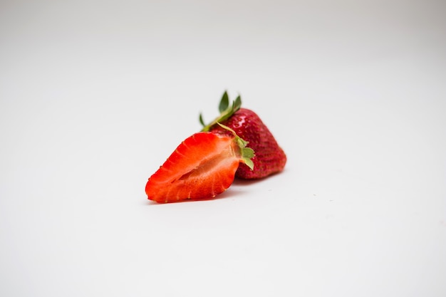 Cortar las fresas en un espacio blanco con espacio libre. Fresas rojas enteras y media.