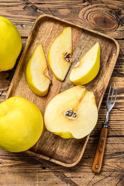 Cortar los frutos de membrillo amarillo en una bandeja de madera