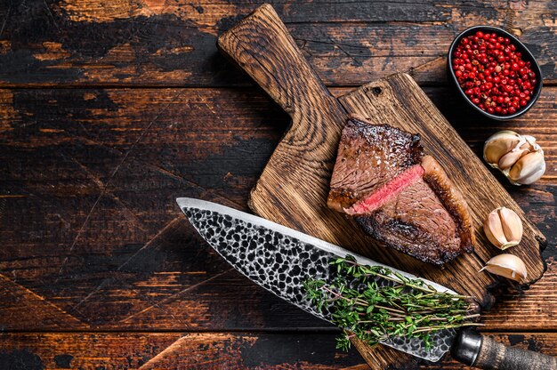 Cortar el gorro de rabadilla frito o bistec de carne de res picanha brasileña en una tabla de madera