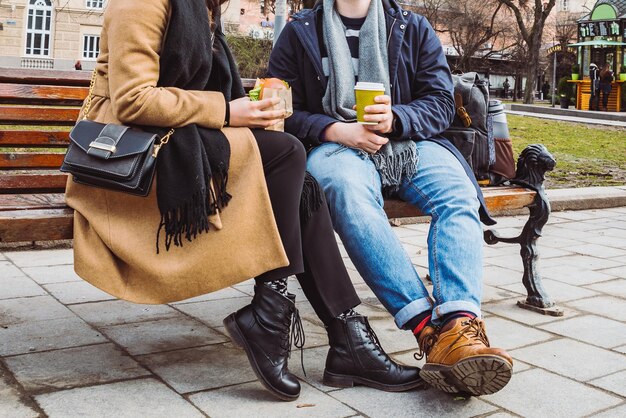 Cortar imagem casal sentado no banco comendo fast-food bebendo chá