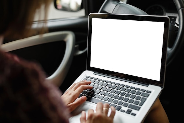 Cortar imagem de maquete de mulher casual assistindo e usando laptop enquanto está sentado no banco do motorista no carro