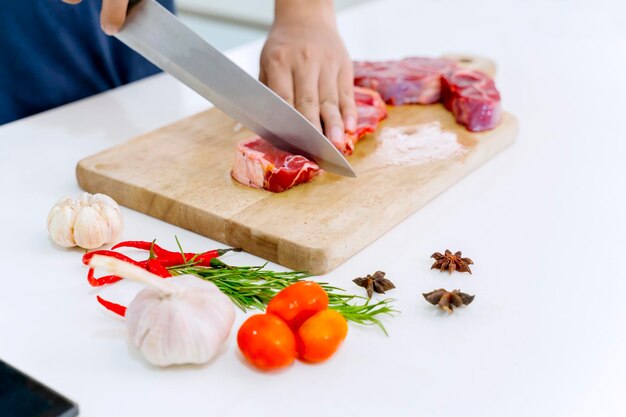 Cortar a mano la carne roja en una tabla de cortar aceitosa