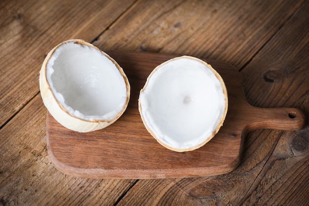 Cortar la mitad de coco y cocos frescos en la mesa de madera antigua para la comida