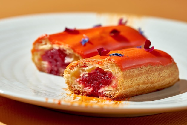 Cortar por la mitad eclair con relleno de bayas y natillas en un plato Closeup profundidad de campo