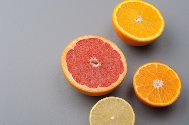 Cortar por la mitad limón fresco, pomelo, naranja, mandarina sobre un fondo gris, vista superior. Ingredientes de jugo de cítricos, Fondo de alimentos
