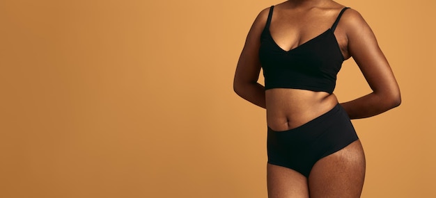 Cortar mulher negra plus size em cueca contra fundo laranja