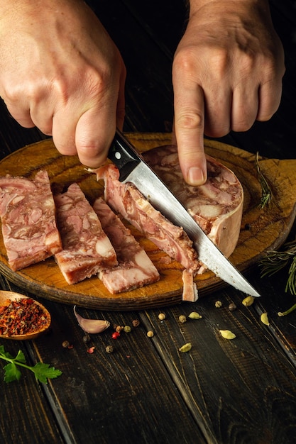 Cortar músculos em uma tábua de cortar com uma faca nas mãos de um cozinheiro ideia de lanche rápido com queijo de cabeça com especiarias aromáticas