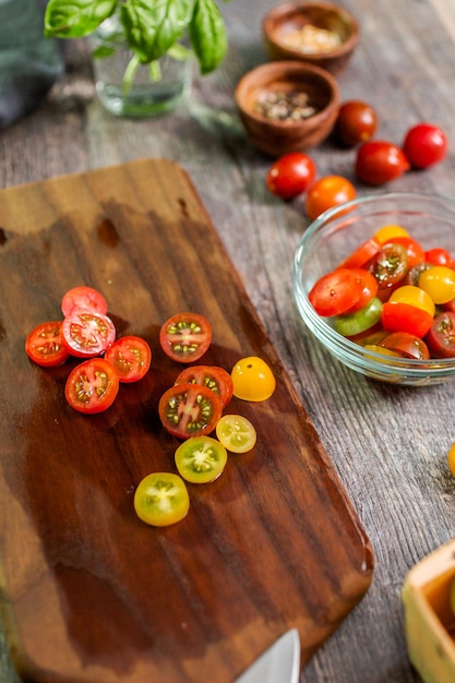 Cortar os tomates cereja da herança na tábua de madeira.