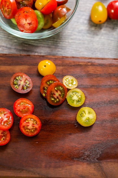 Cortar os tomates cereja da herança na tábua de madeira.