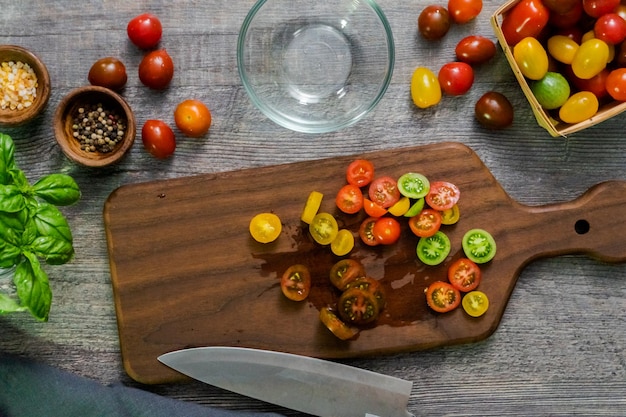 Cortar os tomates cereja da herança na tábua de madeira.