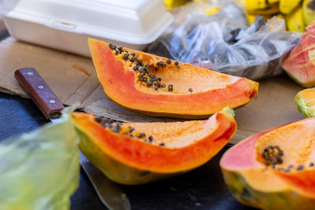 Cortar papaya al lado de la mesa anciano prepara cóctel de frutas